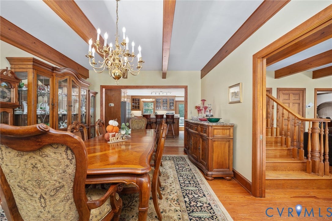Hardwood flooring, exposed wood beam ceiling, brass chandelier, wood staircase, and wood trim throughout