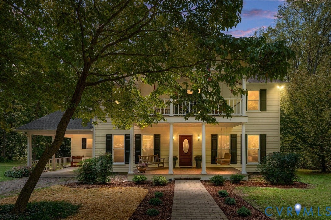 Two-story residence with a covered front porch, an upper-level balcony, and a brick paver walkway leading to the entrance