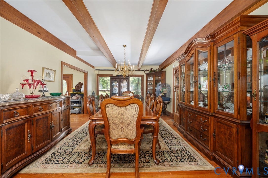 Exposed ceiling beams, wood-finish flooring, built-in display cabinetry, cased opening, chandelier