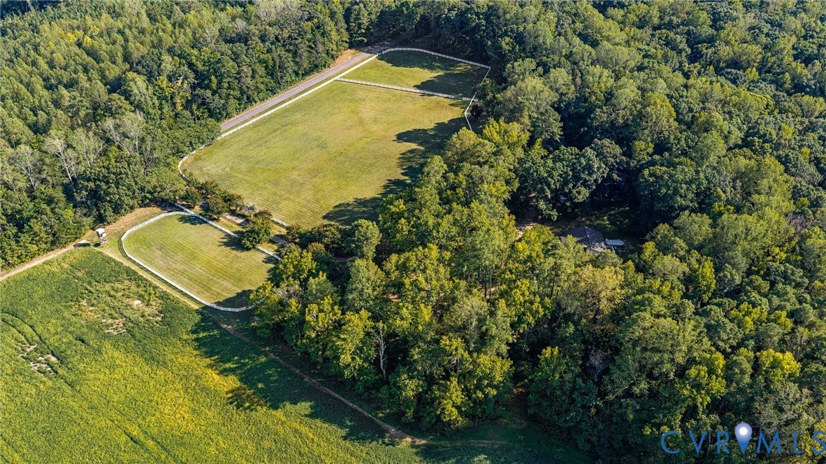 Expansive property featuring wooded areas, multiple cleared fields, and a private dwelling surrounded by mature trees