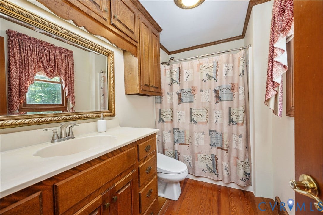 Bathroom featuring a wood-finish vanity with an integrated sink, a large framed mirror, and a built-in wood-finish cabinet