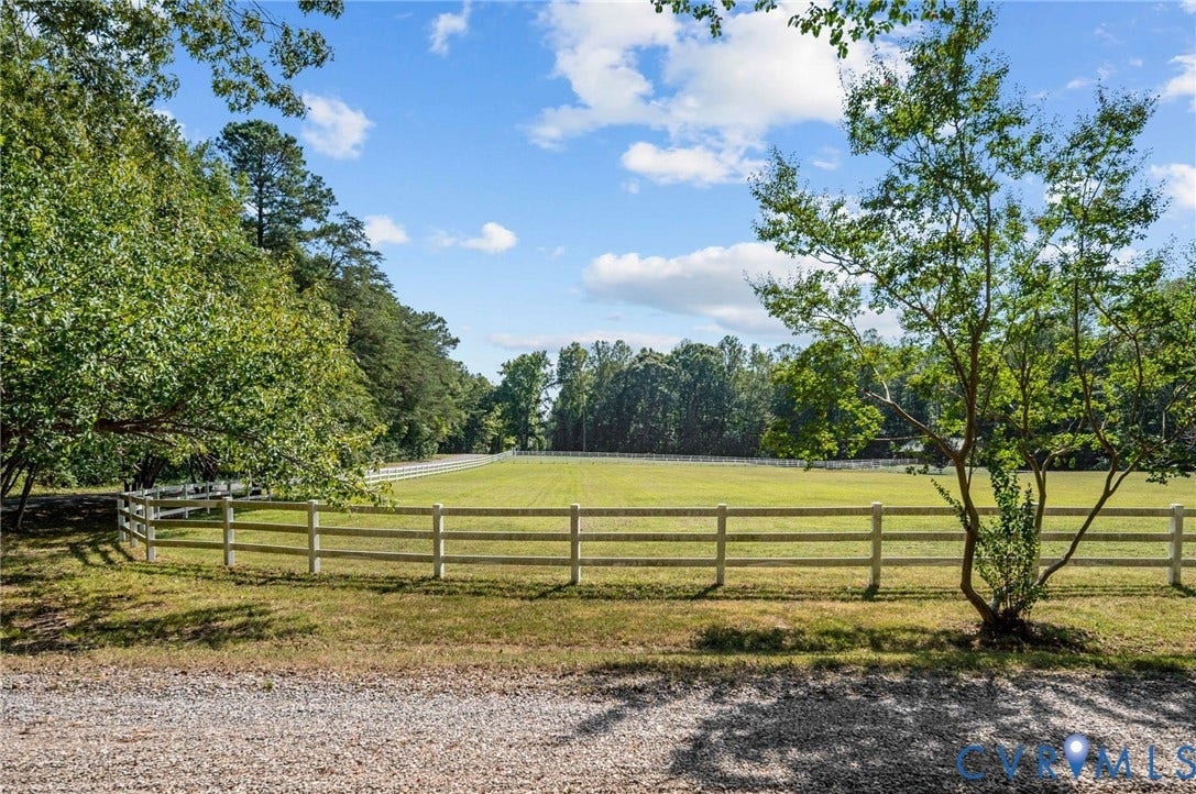Expansive grass pasture with perimeter fencing, surrounded by mature trees
