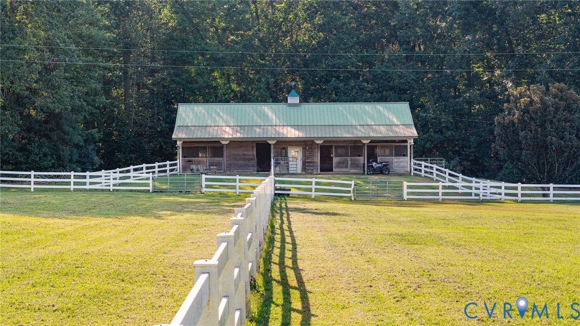 Wood-sided structure featuring a green metal roof and a covered porch
