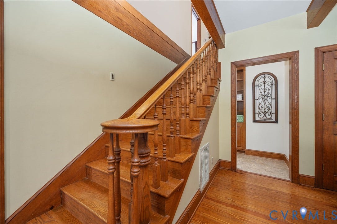 Hardwood flooring, wood staircase with turned balusters, wood door frame, and wood door