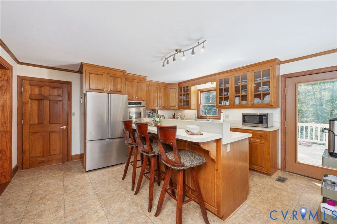 Kitchen featuring wood cabinetry, stainless steel refrigerator, white countertops, tile flooring, and track lighting