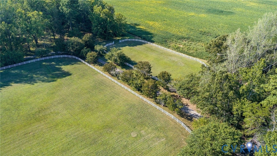 Expansive green fields, mature trees, white perimeter fencing, and a natural landscape