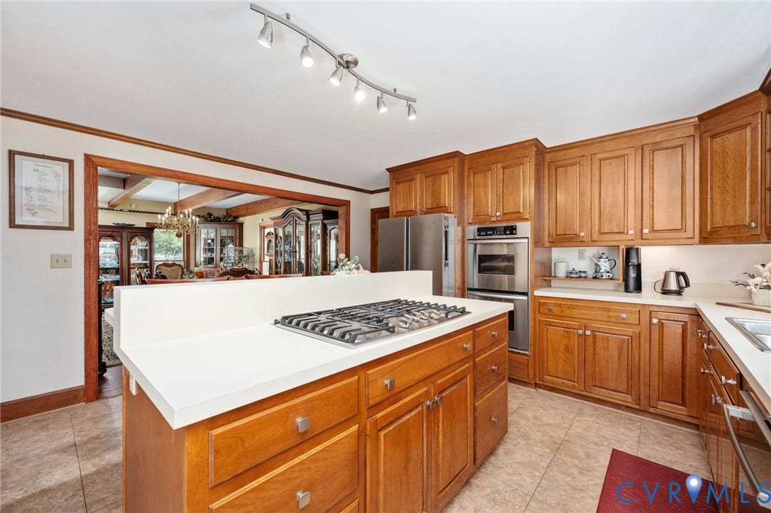Kitchen featuring wood cabinetry, stainless steel appliances, a center island with a cooktop, and tile flooring