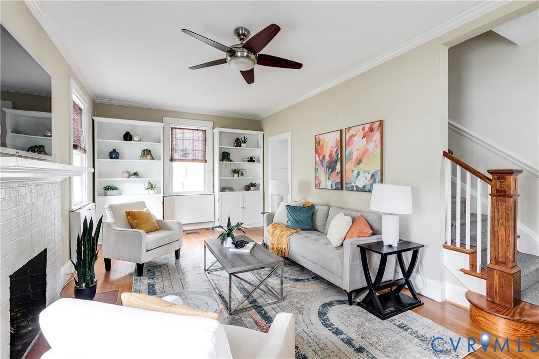 4015 Mount Vernon Street, Bellevue, Richmond, VA 23227 Hardwood flooring, white built-in shelving, white brick fireplace, wood staircase with white balusters, and a ceiling fan with wood-finish blades