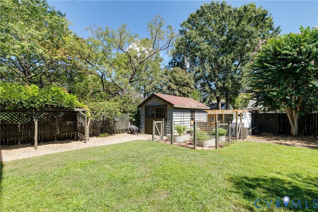 4015 Mount Vernon Street, Bellevue, Richmond, VA 23227 Expansive backyard featuring a lush lawn, a detached storage shed, raised garden beds, a trellis structure, and privacy fencing