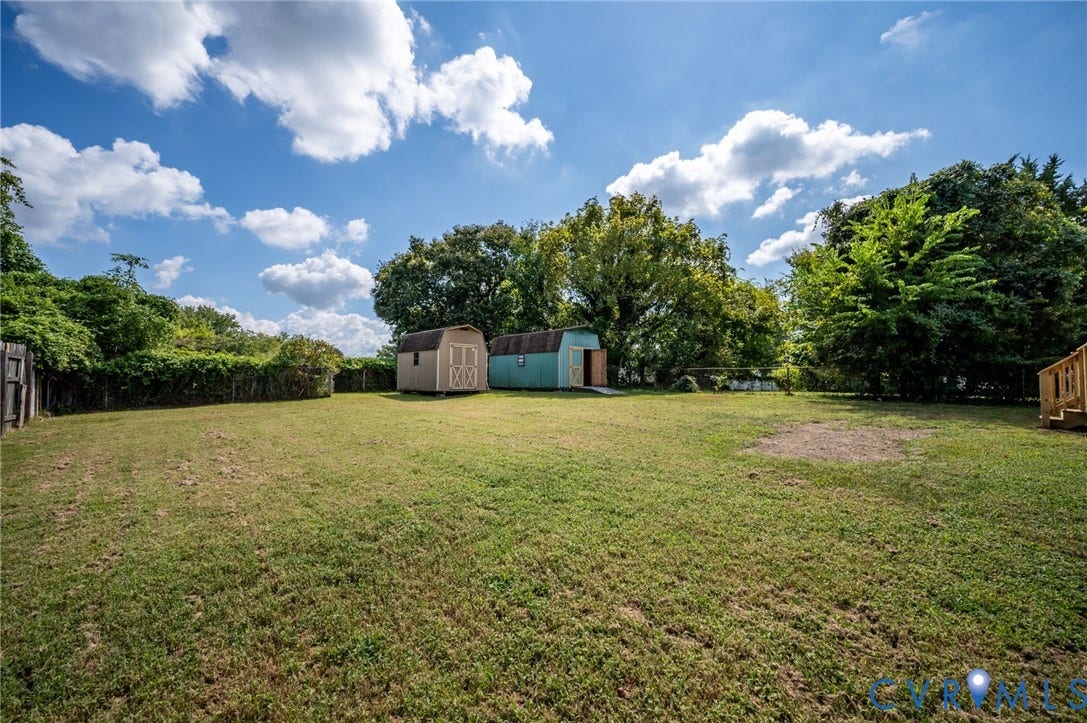 4411 Samara Drive, Henrico, VA 23231 Expansive grassy yard with mature trees, two storage sheds, and a wood privacy fence