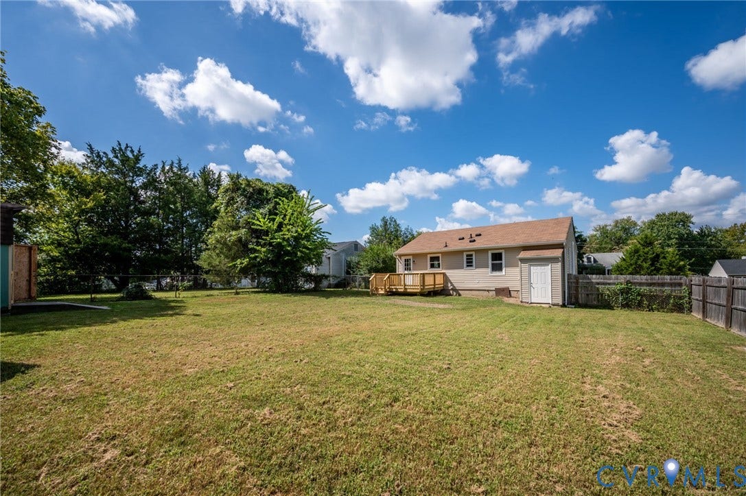 4411 Samara Drive, Henrico, VA 23231 Expansive grassy yard with a wood-fenced perimeter, featuring a wood deck and an exterior storage shed