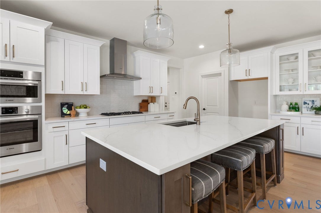 2871 Old Pump Road, The Preserve At John Rolfe, Henrico, VA 23233 White cabinetry with brushed brass hardware, stainless steel built-in appliances, a central island with an integrated sink, pendant lighting, and wood-finish flooring