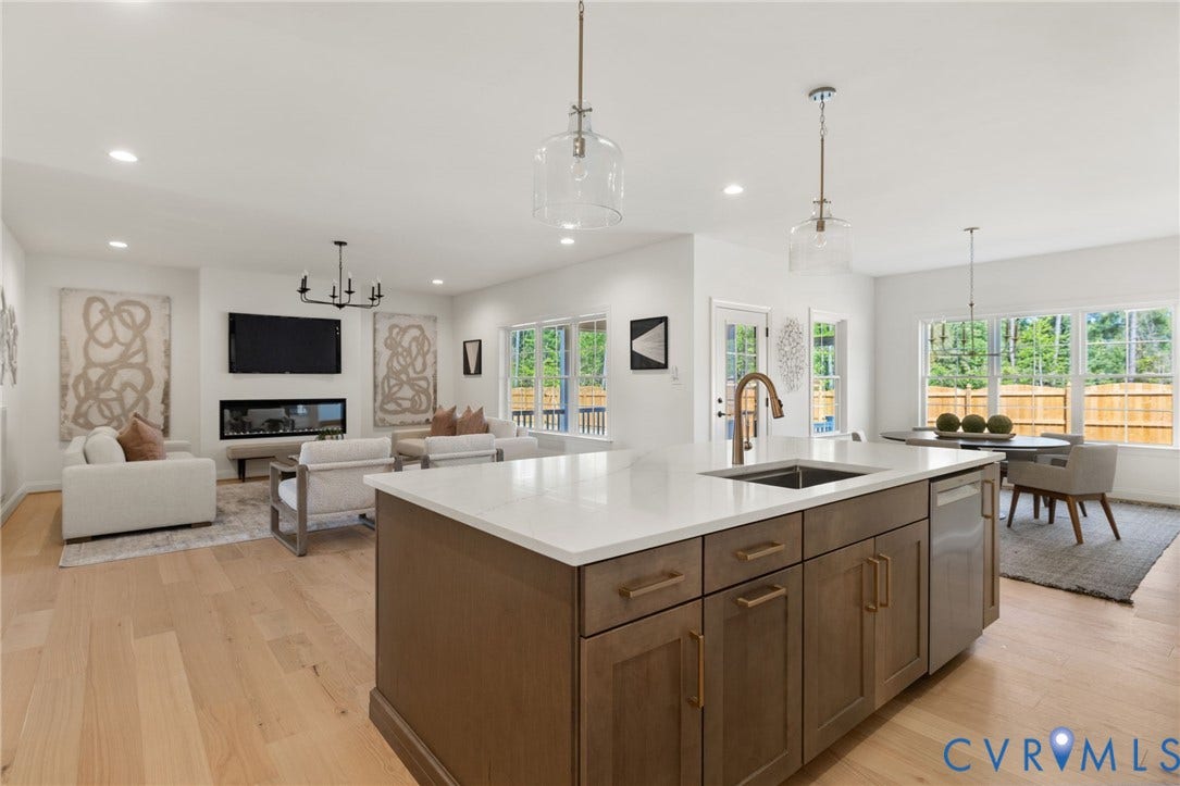 2871 Old Pump Road, The Preserve At John Rolfe, Henrico, VA 23233 Open-concept living space featuring wood-finish flooring, a kitchen island with stone countertops, a linear fireplace, and extensive windows