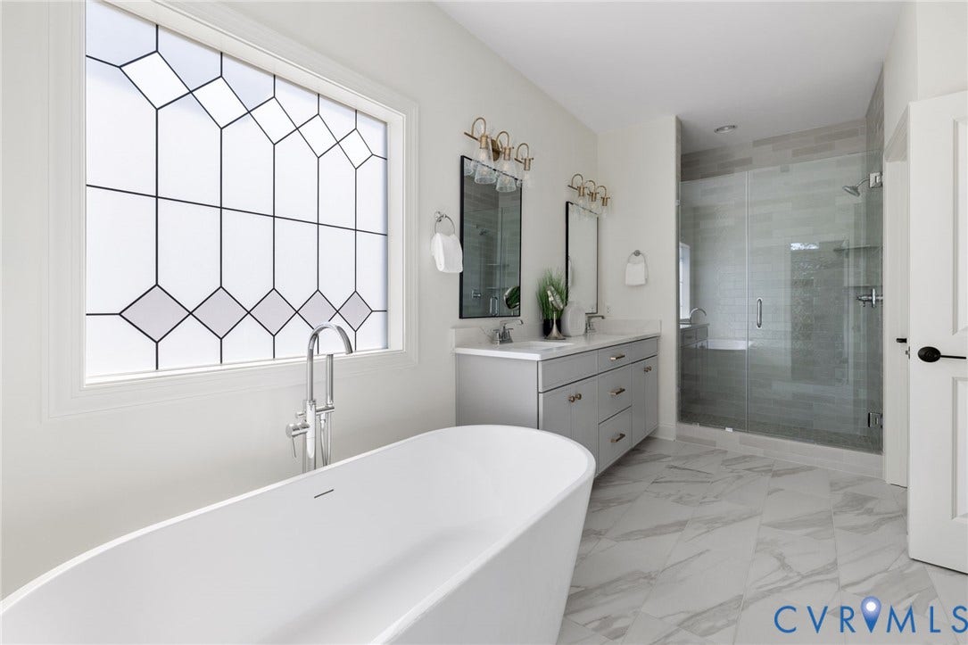 2871 Old Pump Road, The Preserve At John Rolfe, Henrico, VA 23233 Freestanding soaking tub with a floor-mounted faucet, dual vanity with undermount sinks, frameless glass-enclosed shower, geometric patterned privacy window, and large format tile flooring