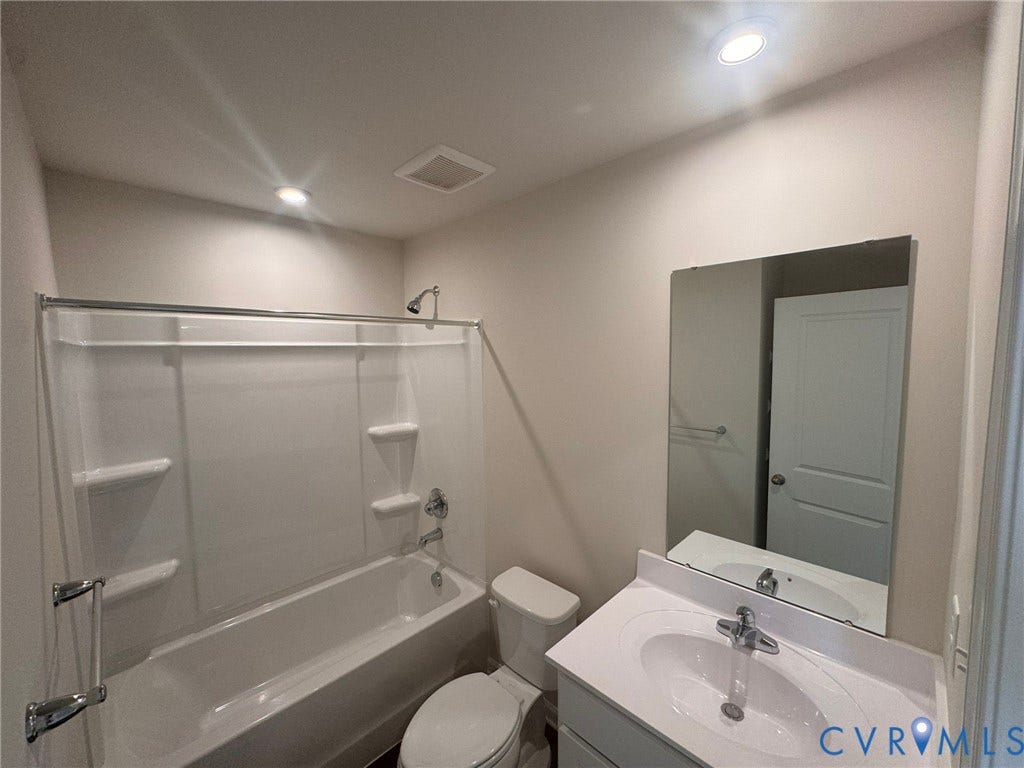 White vanity with integrated sink, chrome faucet, and expansive wall-mounted mirror