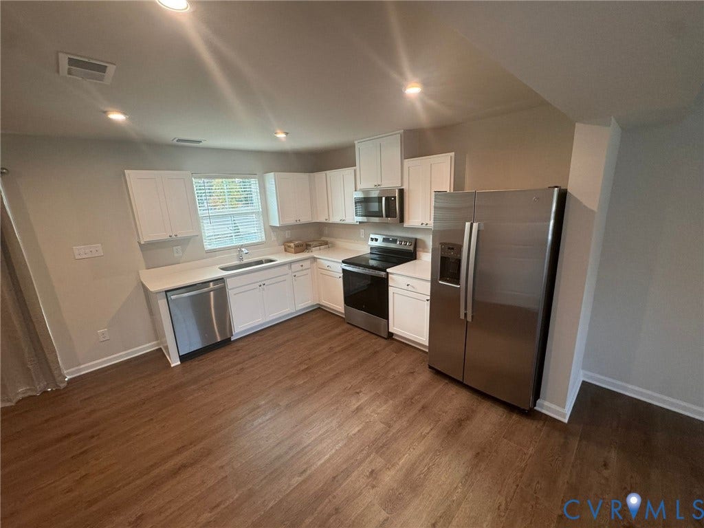 Kitchen featuring wood-finish flooring, white cabinetry, stainless steel appliances, and recessed lighting