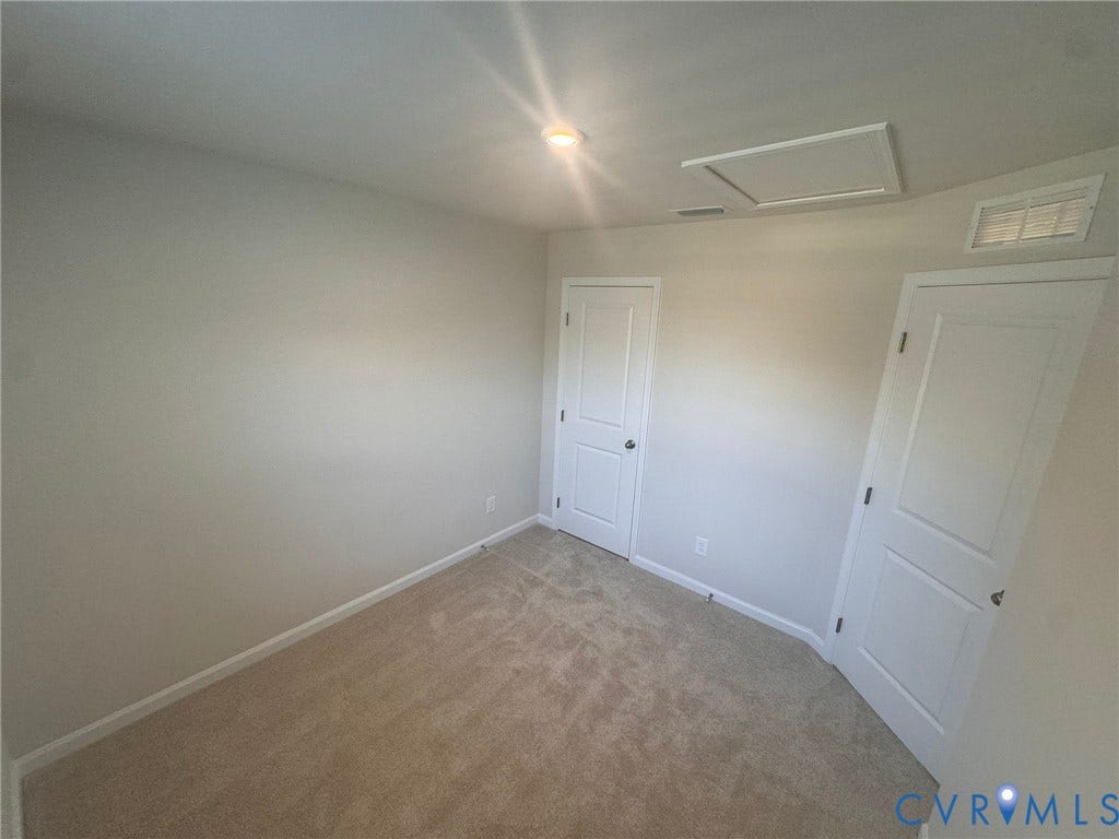 Carpeted room featuring light-colored walls, white trim, and white paneled doors