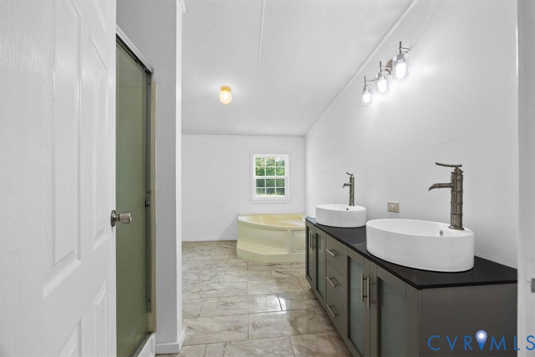 274 Frenchs Store Road, Cumberland, VA 23040 Double vanity with rectangular vessel sinks, matte-finish faucets, dark-toned cabinetry, tile flooring, and a corner soaking tub, separate shower