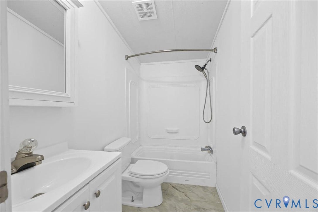 274 Frenchs Store Road, Cumberland, VA 23040 Main Hall Bathroom featuring a vanity cabinet with a integrated sink, a built-in medicine cabinet with mirror, a toilet, a shower and tub combination with a handheld shower head, and patterned flooring