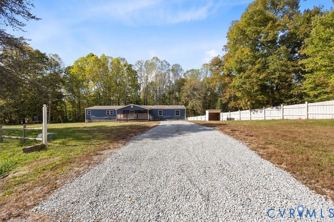 274 Frenchs Store Road, Cumberland, VA 23040 Blue exterior siding, front entry deck, gravel driveway, and perimeter fencing situated on a wooded lot