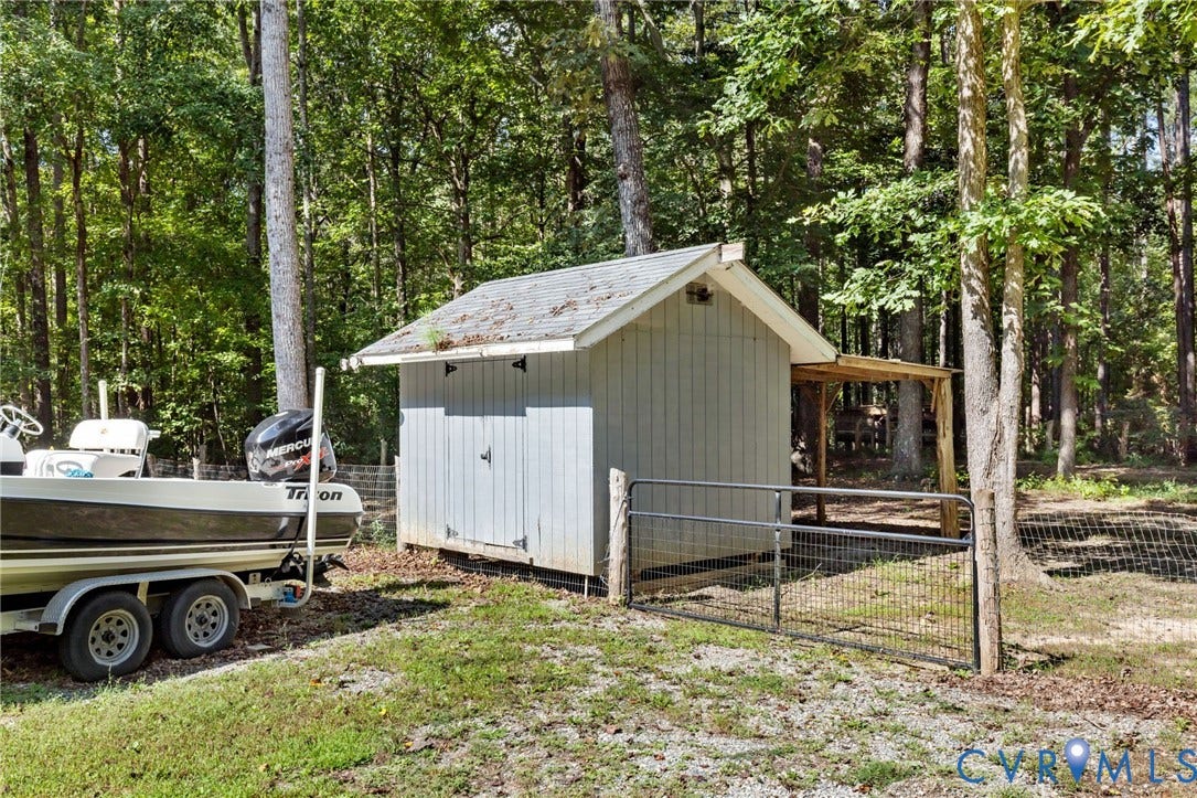 4350 Steger Creek Drive, Powhatan, VA 23139 Storage shed with an attached covered lean-to, set within a wooded perimeter with a wire fence