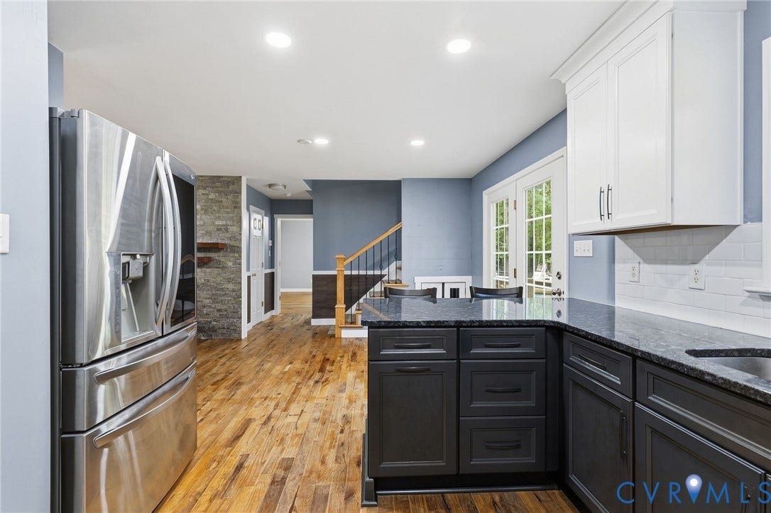 4350 Steger Creek Drive, Powhatan, VA 23139 Stainless steel refrigerator with a built-in dispenser, dark cabinetry with light stone countertops, white upper cabinetry, and a white subway tile backsplash