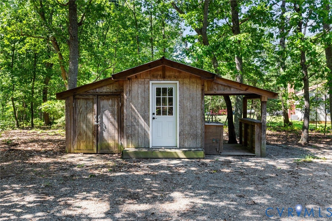 2137 Scarlet Mill Lane, Powhatan, VA 23139 Wood-sided outbuilding with a covered porch entry, a white paneled door, and a dedicated storage area