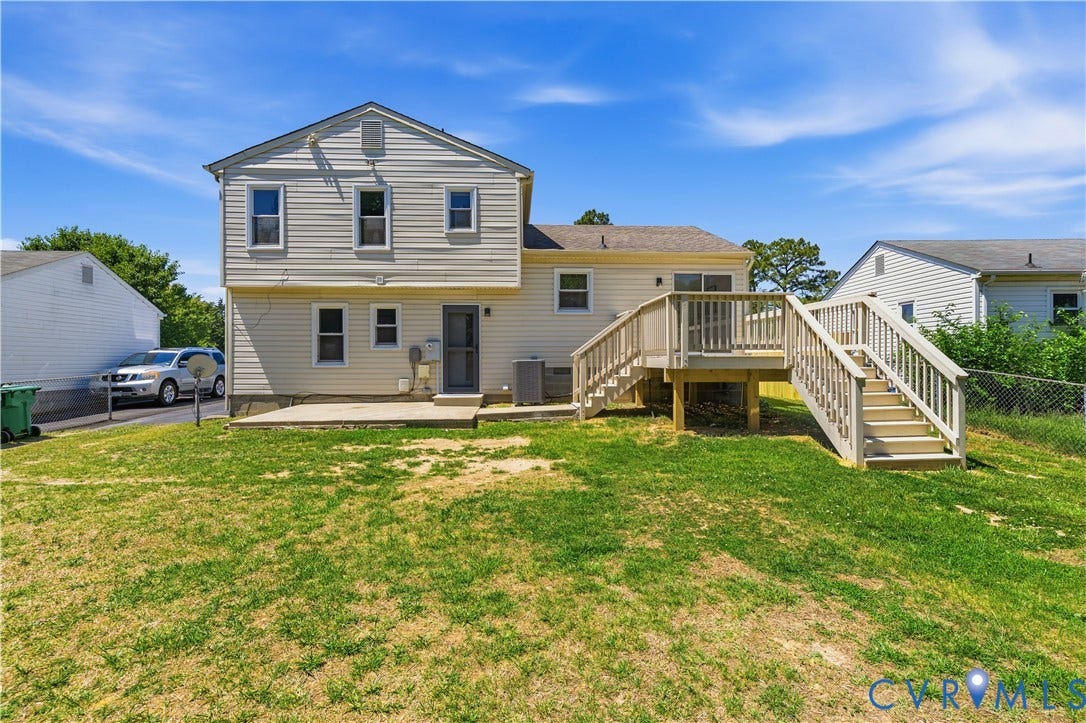 952 Pleasant Street, Henrico, VA 23223 Rear exterior featuring light-colored siding, a multi-level wood-finish deck with railings, an additional ground-level concrete patio, and a grass lawn