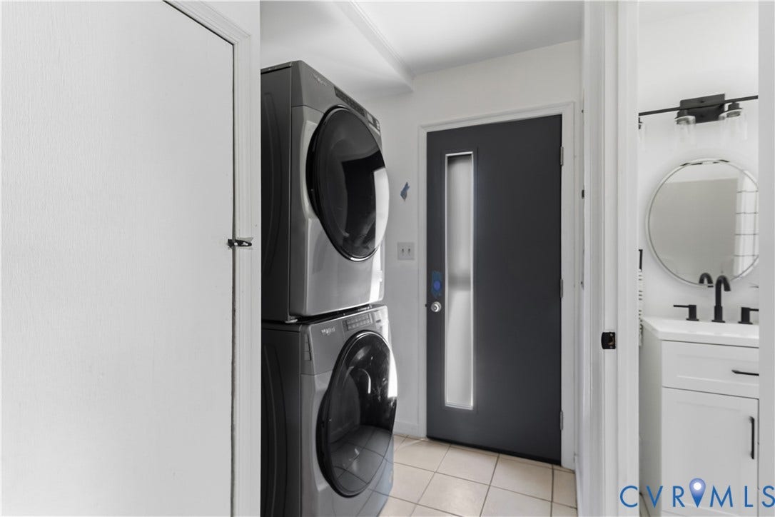 952 Pleasant Street, Henrico, VA 23223 Stacked laundry appliances, dark entry door with vertical frosted glass insert, white vanity with integrated sink, black faucet, and circular mirror