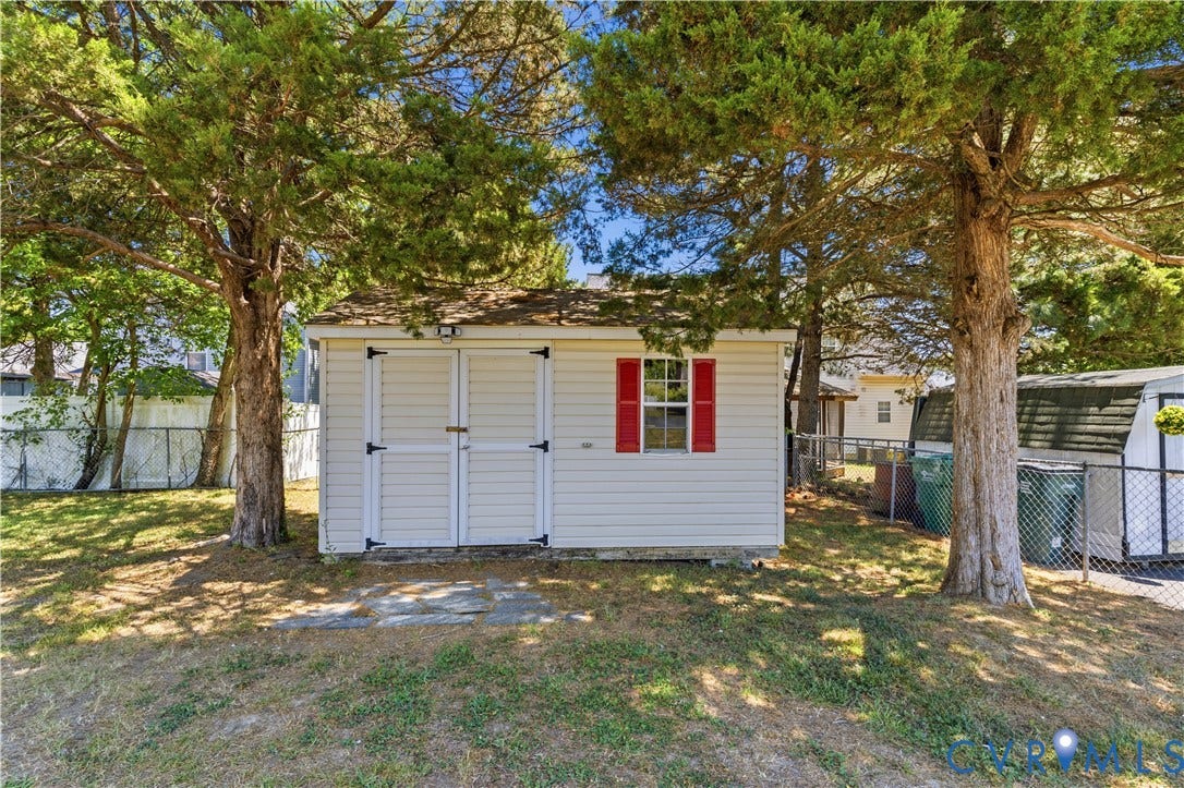 952 Pleasant Street, Henrico, VA 23223 Storage shed with white siding, a shingled roof, double entry doors, and a window with red shutters