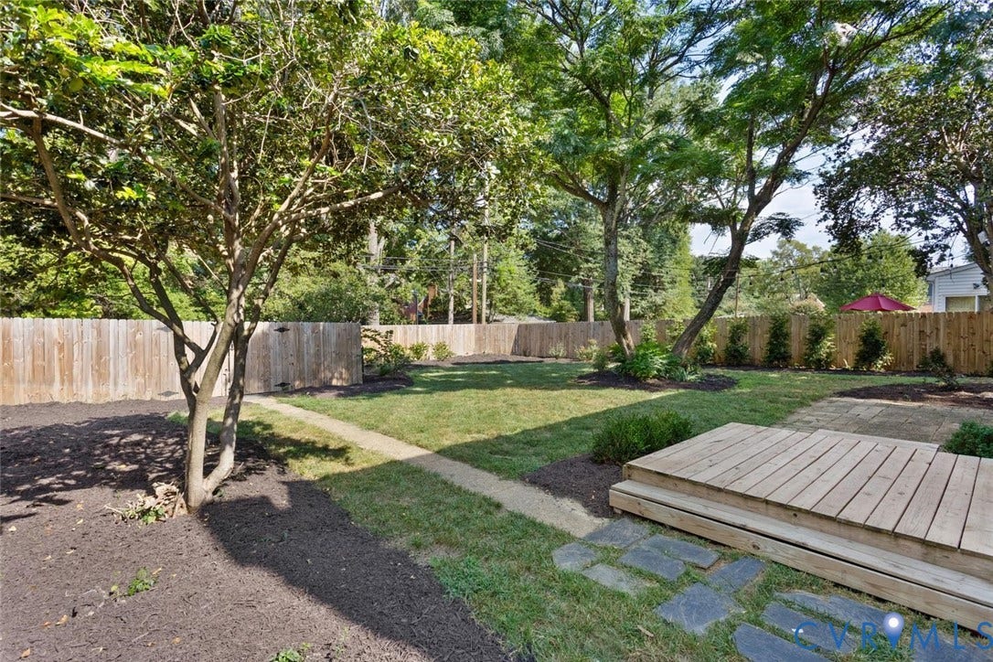 1316 Brookland Parkway, Richmond, VA 23227 Expansive backyard featuring a natural wood fence, mature trees, a wooden deck, stone pavers, and landscaped garden beds