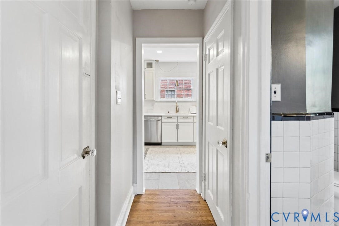 1316 Brookland Parkway, Richmond, VA 23227 Wood-finish flooring, white paneled doors with clear glass knobs, and a hallway leading to a kitchen with white cabinetry and stainless steel appliances