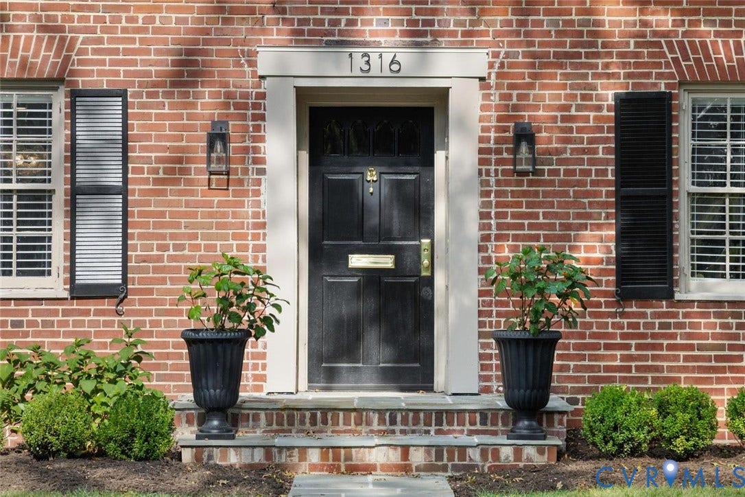 1316 Brookland Parkway, Richmond, VA 23227 Brick exterior featuring a paneled front door, decorative exterior lighting, and louvered window shutters