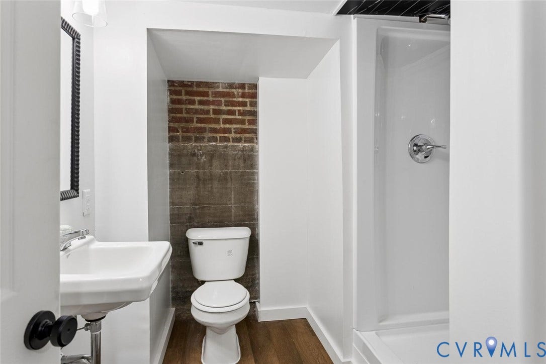 1316 Brookland Parkway, Richmond, VA 23227 White pedestal sink with chrome faucet, toilet, exposed brick wall feature, and white shower stall with chrome fixtures