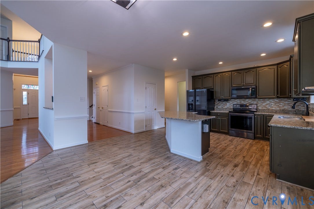 Kitchen featuring dark cabinetry, stainless steel appliances, granite countertops, and a tiled backsplash