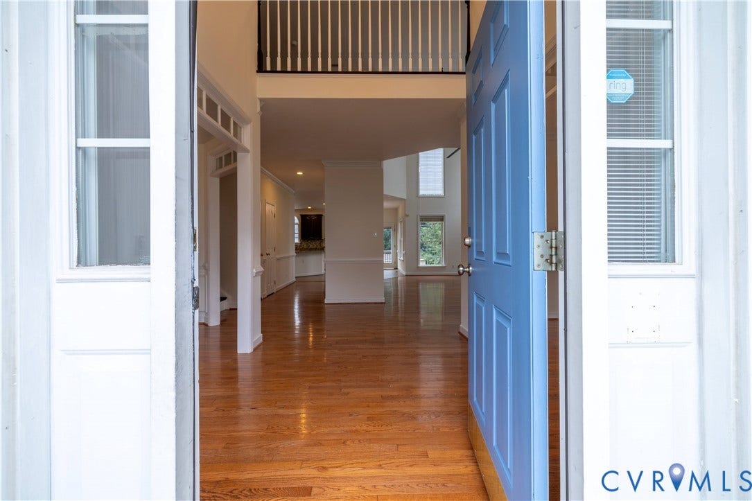 Entry foyer featuring wood-finish flooring, a two-story ceiling, a second-level railing, and extensive trim work