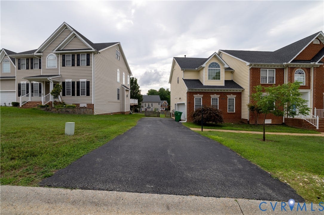 Asphalt driveway accessing brick and siding exteriors