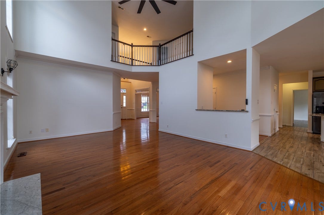 Hardwood flooring, two-story ceiling, upper-level railing, built-in breakfast bar, and fireplace mantel