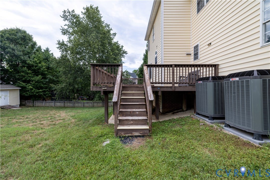 Expansive backyard featuring a wood deck with stairs, a storage shed, and a privacy fence