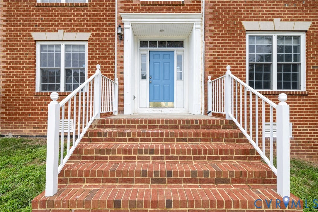 Brick exterior with a prominent entrance featuring a blue door
