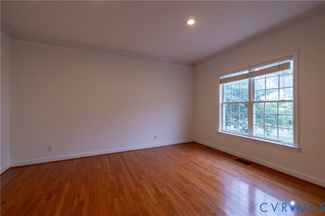 Hardwood flooring, crown molding, recessed lighting, and a double-hung window