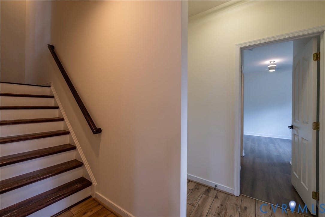 Staircase with wood-finish treads and risers, dark wood-finish handrail, and light-toned walls