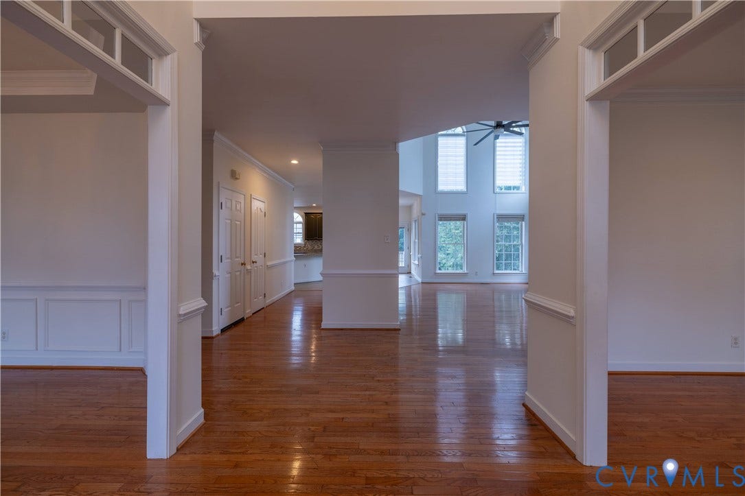 Hardwood-finish flooring, white paneled wainscoting, white trim, recessed lighting, and a multi-story window feature
