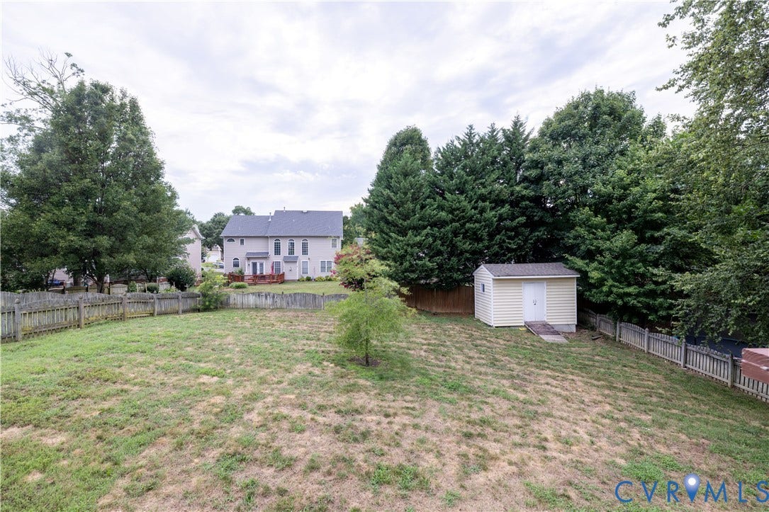 Expansive lawn with perimeter fencing and mature trees