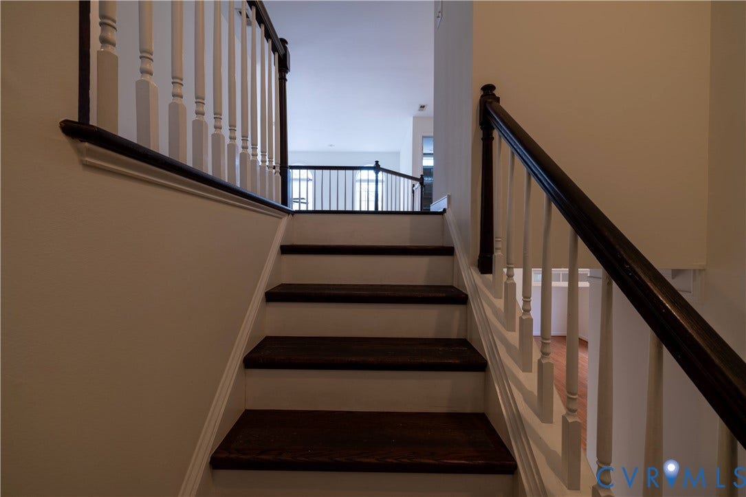 Staircase featuring dark wood-finish treads and risers, white balusters, and a dark wood-finish handrail