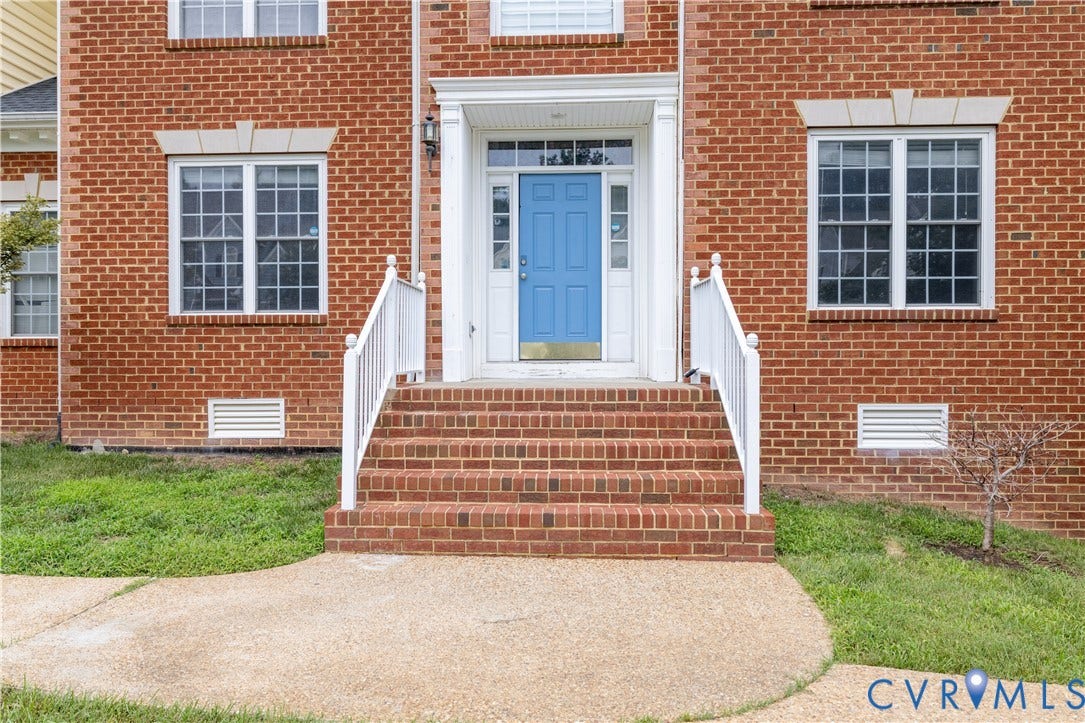 Brick exterior with a vibrant blue entry door, white trim, and white railings