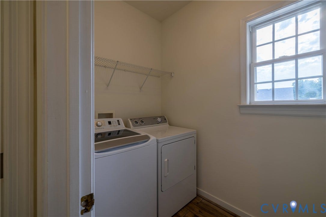 Laundry area featuring wood-finish flooring, a double-hung window, and a built-in wire shelving unit