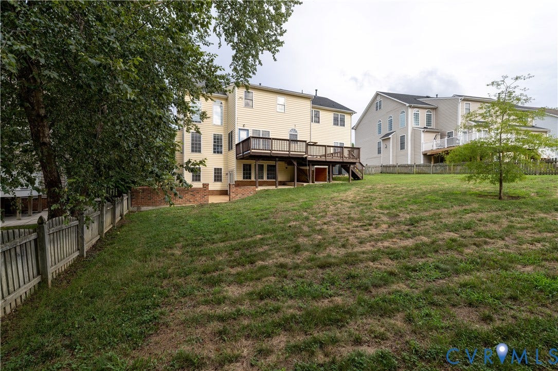 Spacious backyard with a sloped lawn and mature perimeter trees
