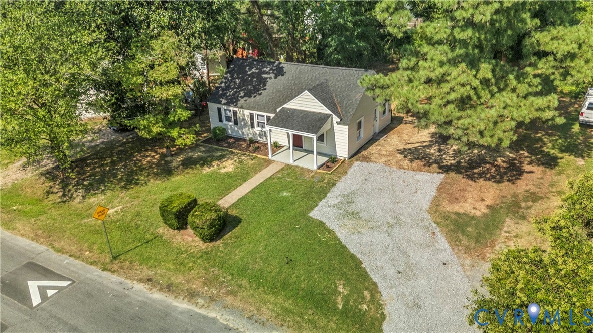 7406 Alycia Avenue, Henrico, VA 23228 Cottage-style residence featuring a covered front porch, gravel driveway, and mature landscaping