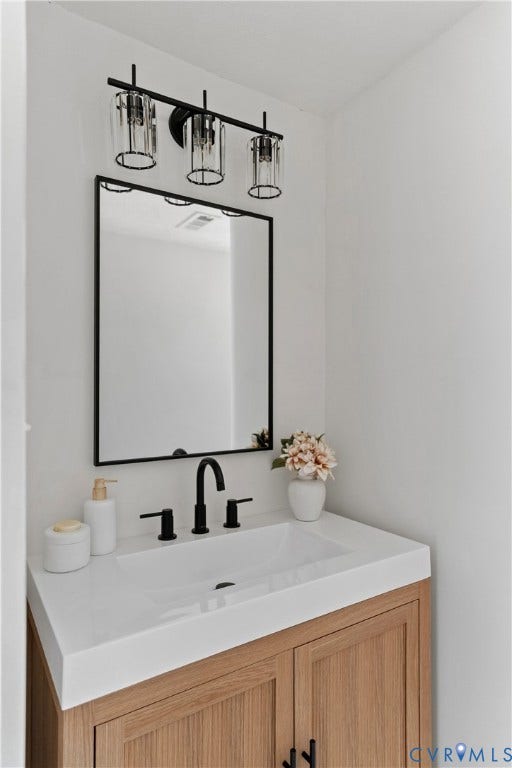 7406 Alycia Avenue, Henrico, VA 23228 White integrated sink with a matte black faucet, set into a light wood-finish vanity with paneling